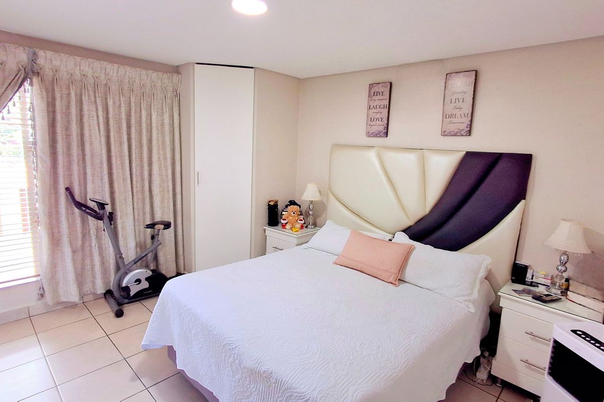 A well-maintained bedroom featuring tiled flooring, a built-in wardrobe, and recessed ceiling lighting, offering a comfortable and functional living space.