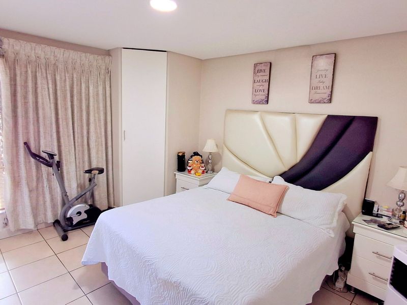 A well-maintained bedroom featuring tiled flooring, a built-in wardrobe, and recessed ceiling lighting, offering a comfortable and functional living space.