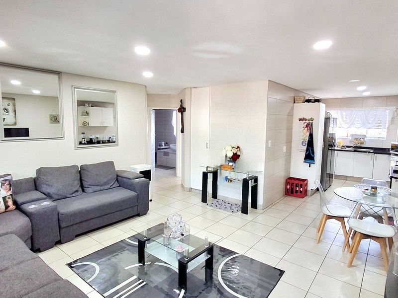 Spacious open-plan living and dining area featuring tiled flooring, recessed lighting, and a functional kitchen with granite countertops and ample cabinetry.