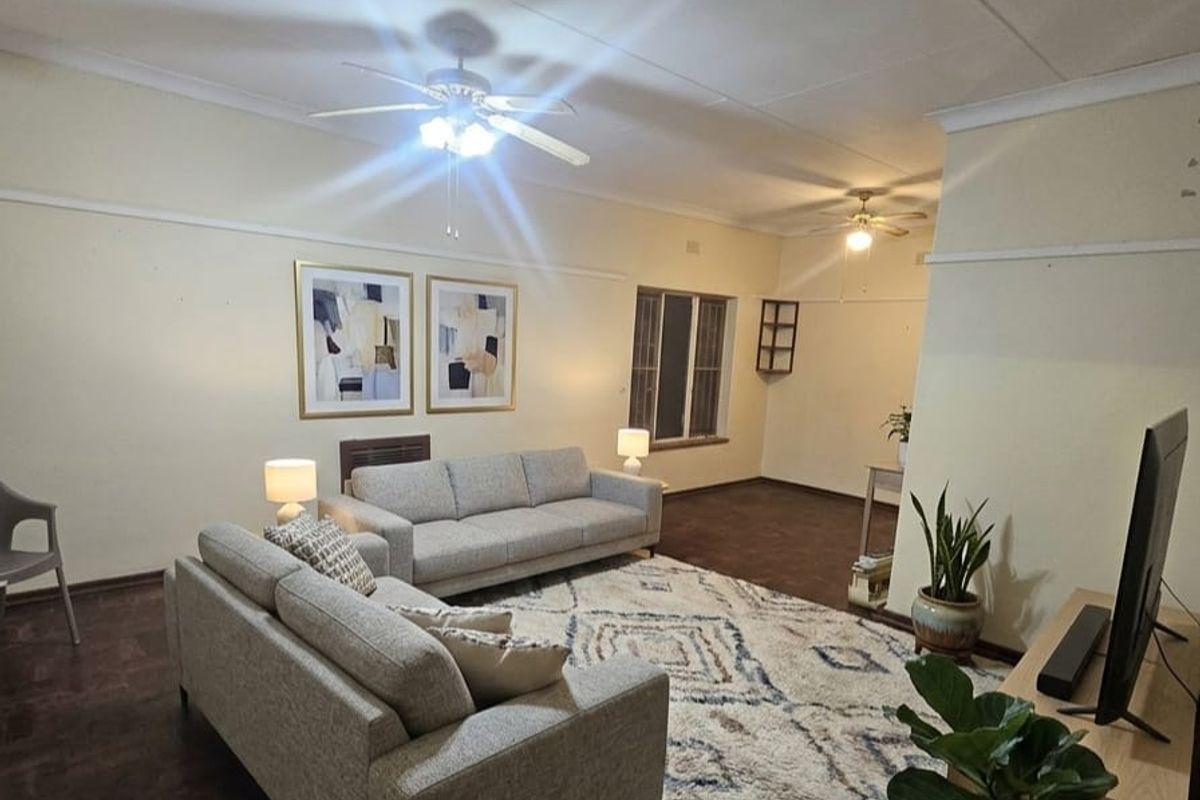 Spacious living room featuring dark parquet flooring, ceiling fans, and classic picture rails, offering a neutral canvas for personalization.