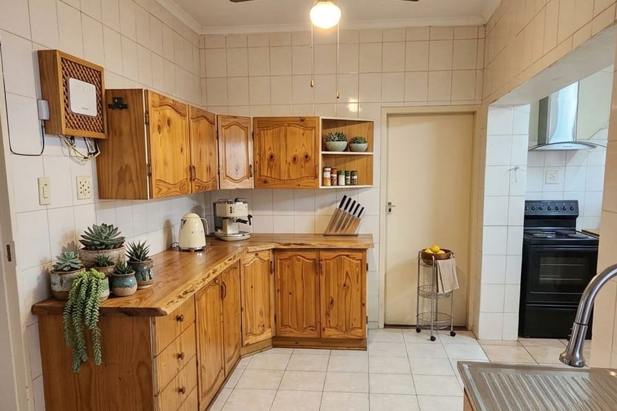 A functional kitchen featuring traditional pine cabinetry, tiled splashbacks, and tiled flooring, with a separate area for the freestanding oven.