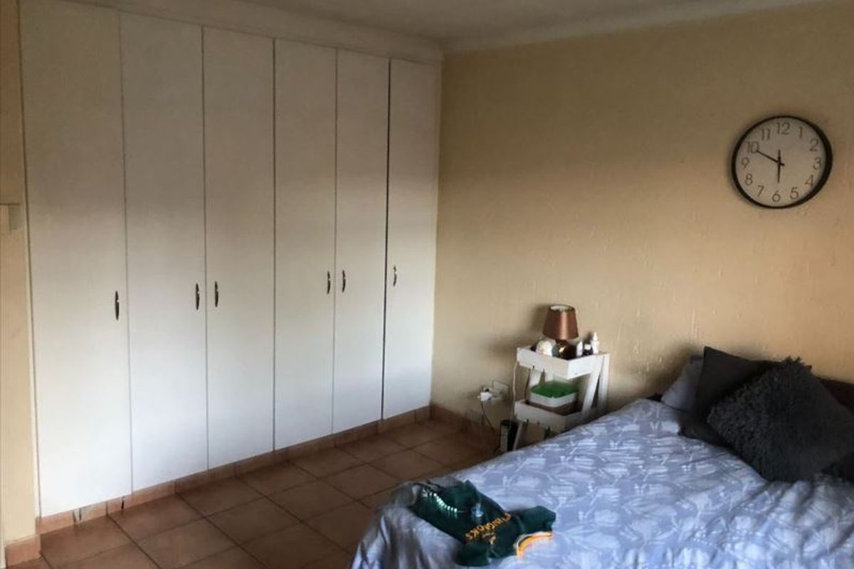 A bedroom featuring built-in floor-to-ceiling cupboards and tiled flooring.