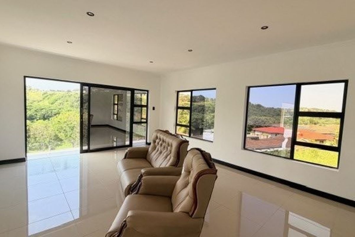 Spacious living area featuring large windows, sliding glass doors, polished tile flooring, and recessed ceiling lighting with scenic views.