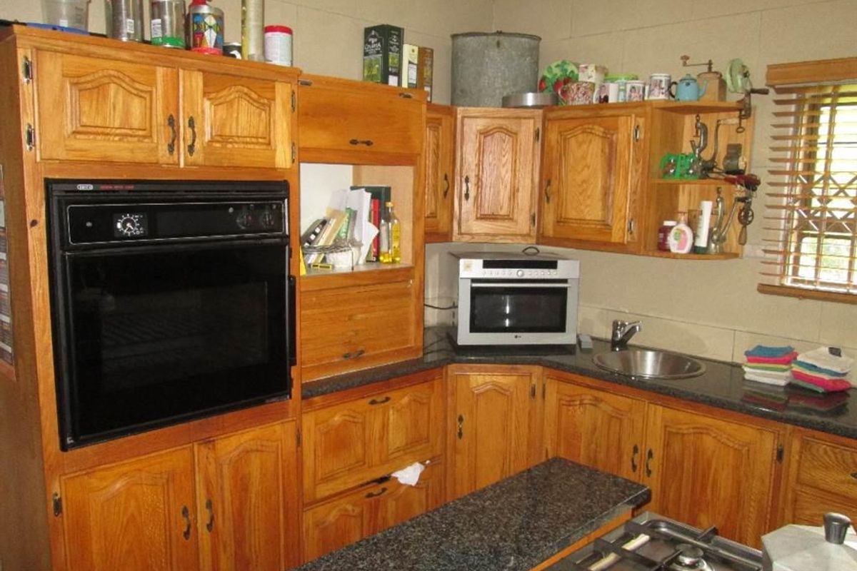 A functional kitchen featuring wooden cabinetry, granite countertops, a built-in oven, and a gas hob, offering a classic layout with ample storage space.