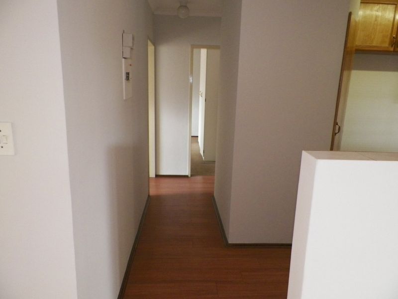 A clean, empty hallway featuring laminate flooring and neutral walls, providing access to multiple rooms within the townhouse.