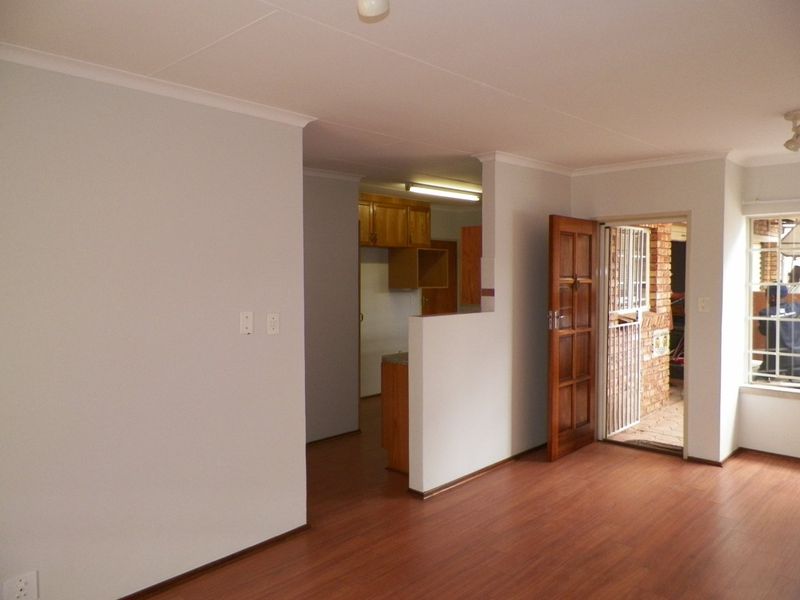 Open plan living area featuring laminate flooring and direct access to an exterior patio, with an adjacent kitchen space.