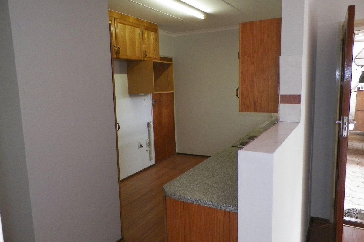 A dated kitchen featuring laminate cabinetry, countertops, and built-in stove, offering a functional layout ready for modernization and cosmetic updates.