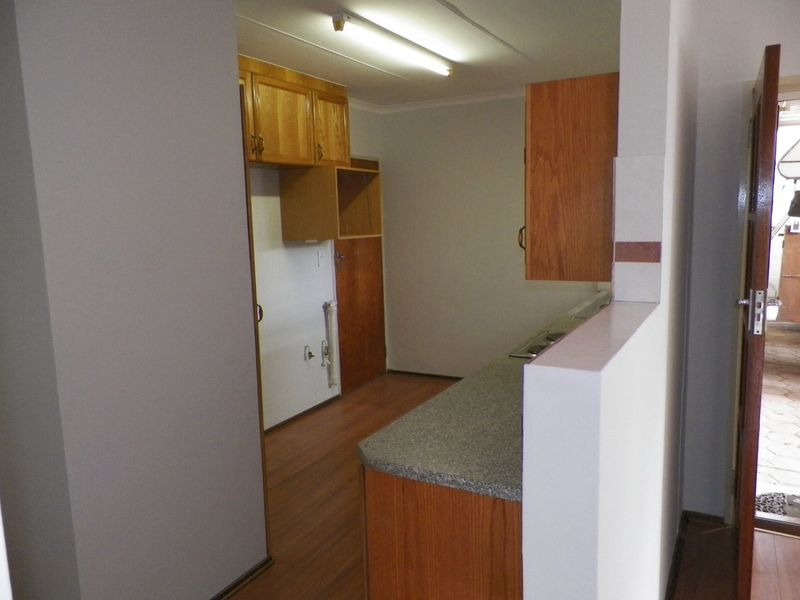 A dated kitchen featuring laminate cabinetry, countertops, and built-in stove, offering a functional layout ready for modernization and cosmetic updates.