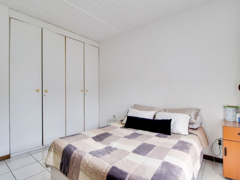 A bedroom featuring built-in cupboards, tiled flooring, and a textured ceiling.
