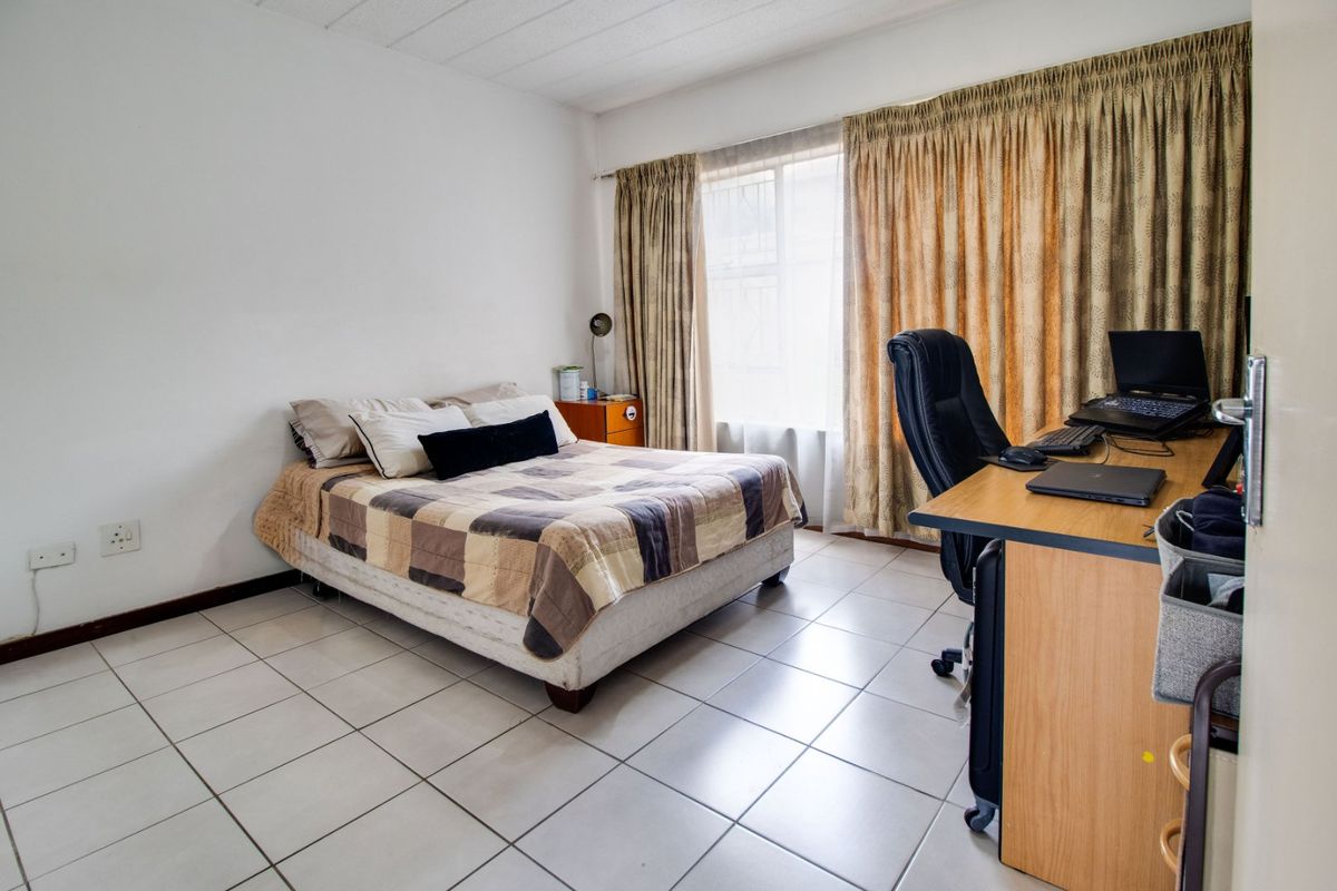 A functional bedroom featuring tiled flooring and large windows with curtain tracks, providing a neutral space ready for personalization.
