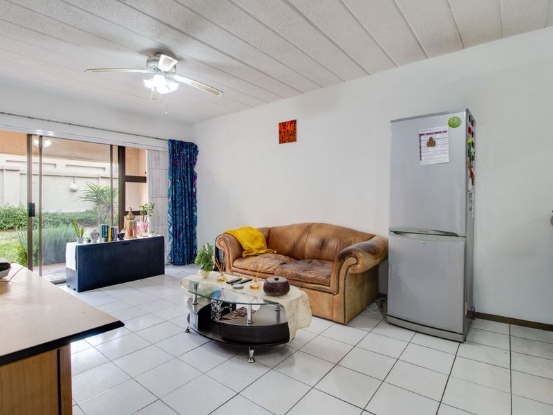 Open-plan living area featuring tiled flooring, a ceiling fan, and large sliding glass doors providing access to the outdoor space.