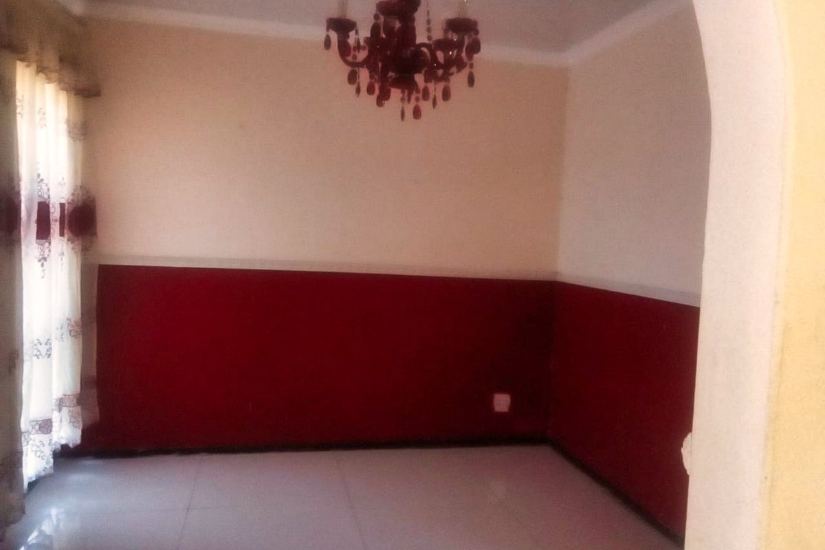 An interior view of a living area featuring tiled flooring, a decorative chandelier, and a two-tone wall finish with a red lower section.