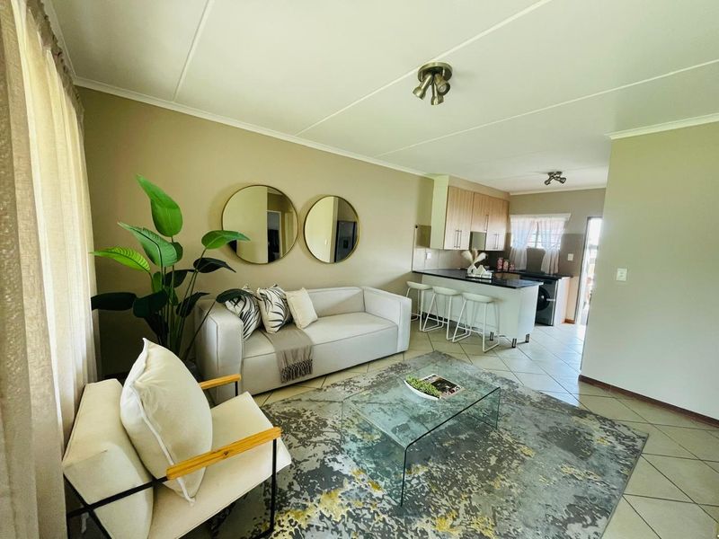 An open-plan living area featuring a kitchen with a breakfast island, tiled flooring, and neutral wall tones, creating a functional and cohesive living space.
