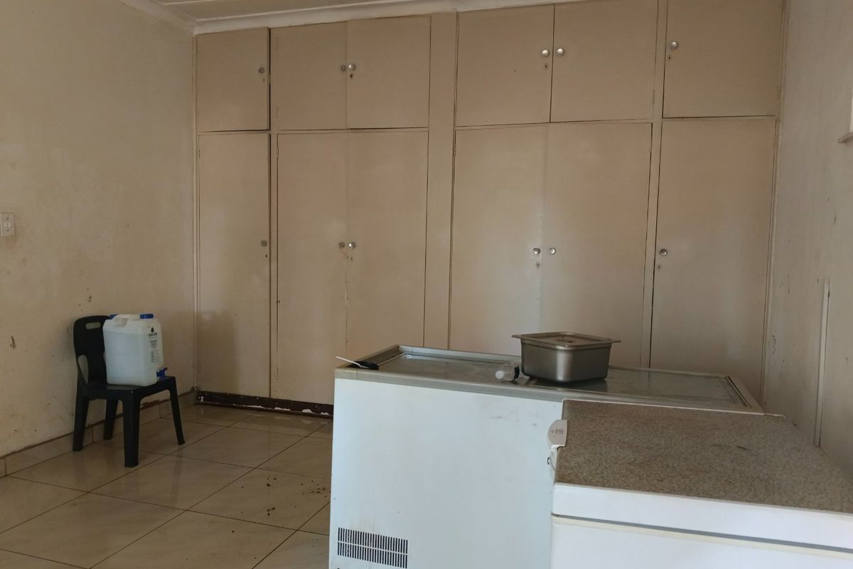 A functional scullery or utility space featuring extensive built-in cabinetry and tiled flooring, offering ample storage potential for a busy household.