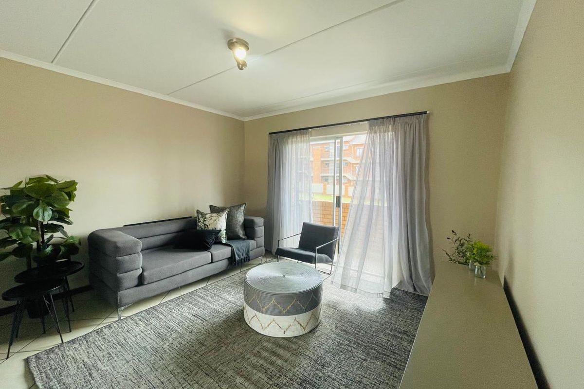 A well-lit living room featuring tiled flooring and a sliding glass door that provides access to an outdoor area.