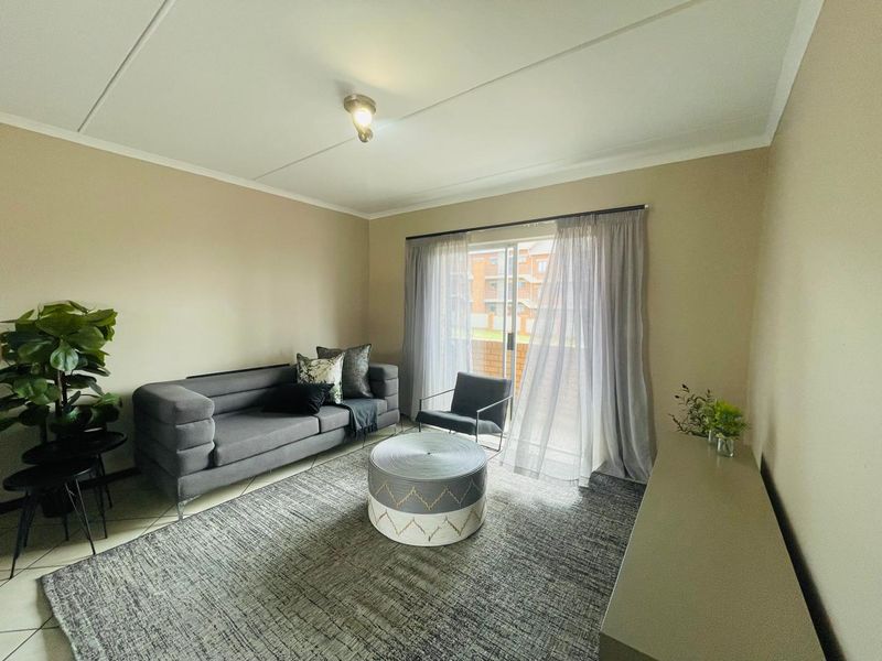 A well-lit living room featuring tiled flooring and a sliding glass door that provides access to an outdoor area.