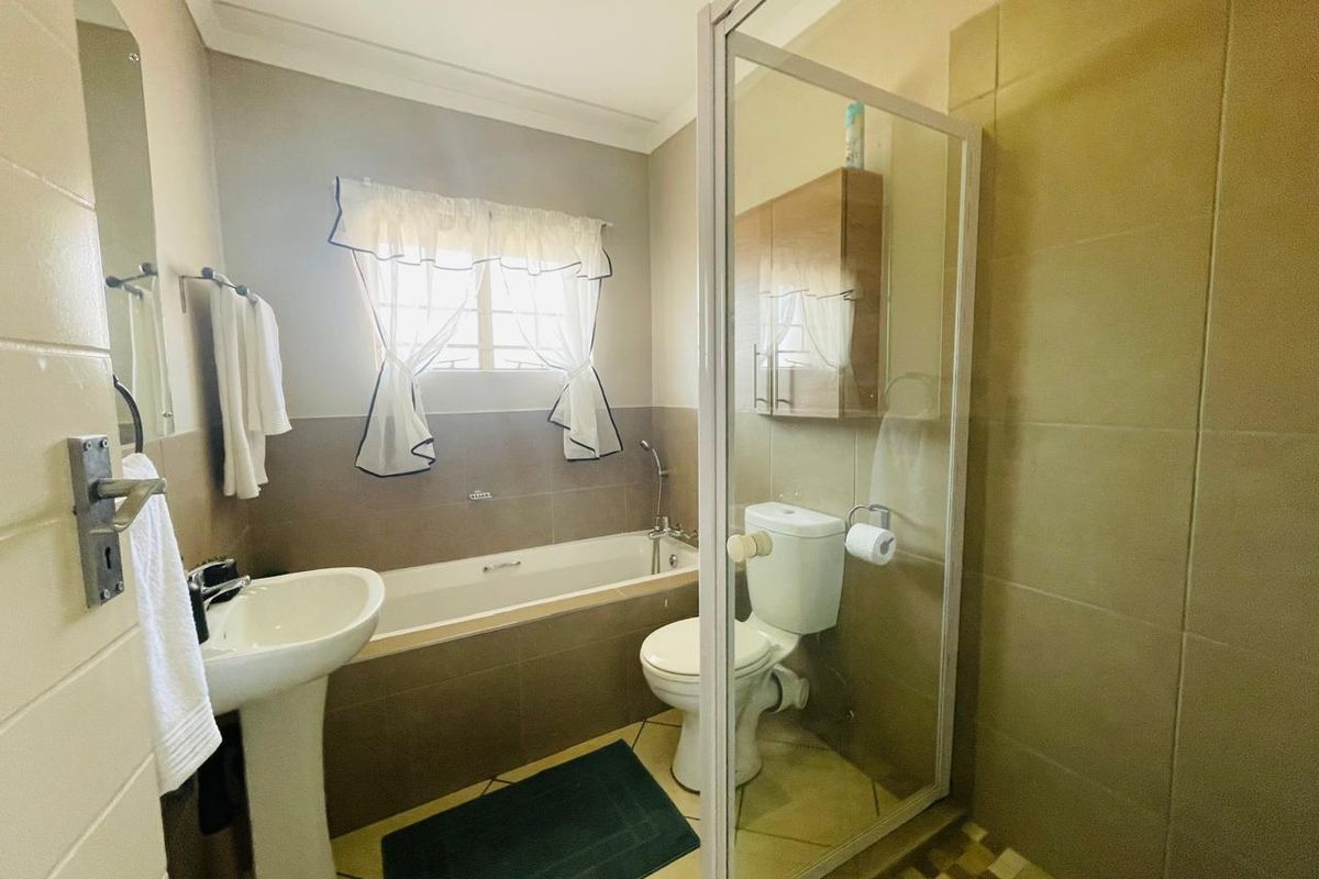A functional bathroom featuring a pedestal basin, bathtub, separate shower enclosure, and tiled finishes throughout.