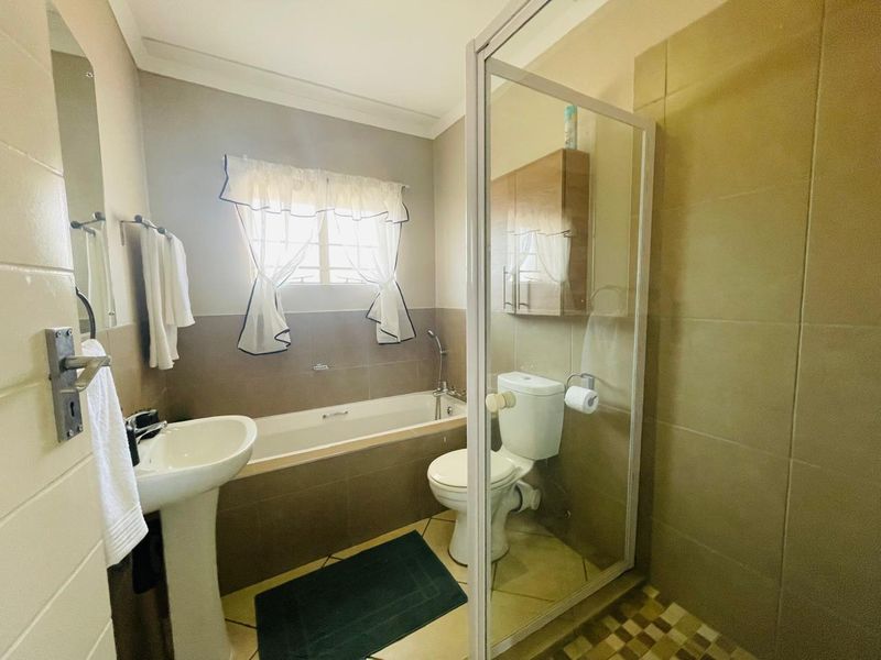 A functional bathroom featuring a pedestal basin, bathtub, separate shower enclosure, and tiled finishes throughout.
