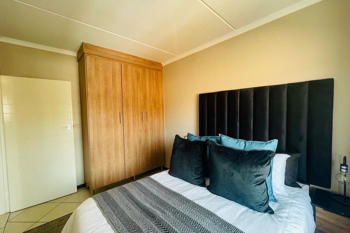 A well-maintained bedroom featuring a built-in wooden wardrobe and tiled flooring, offering a clean and functional living space.