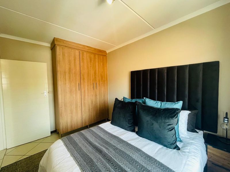 A well-maintained bedroom featuring a built-in wooden wardrobe and tiled flooring, offering a clean and functional living space.