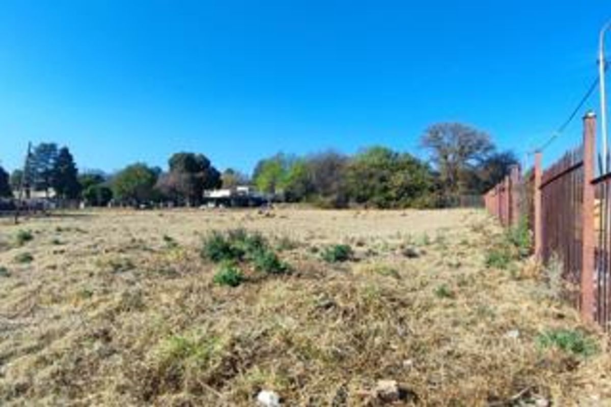 A view of a vacant residential plot featuring established perimeter metal fencing and open, cleared land.