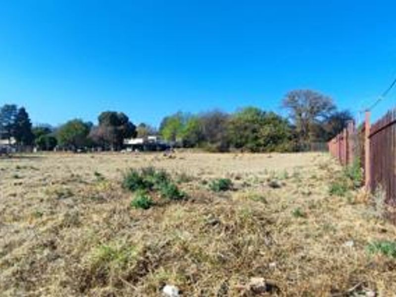 A view of a vacant residential plot featuring established perimeter metal fencing and open, cleared land.