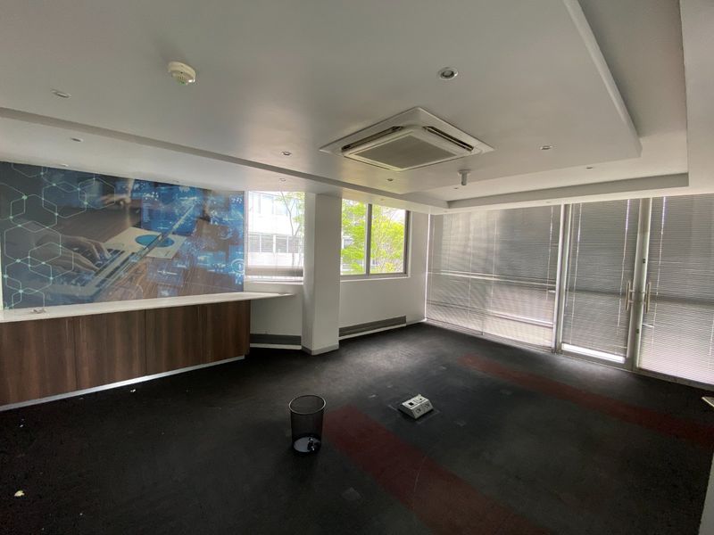 A vacant commercial office space featuring built-in cabinetry, recessed ceiling lighting, ducted air conditioning, and large windows with venetian blinds.