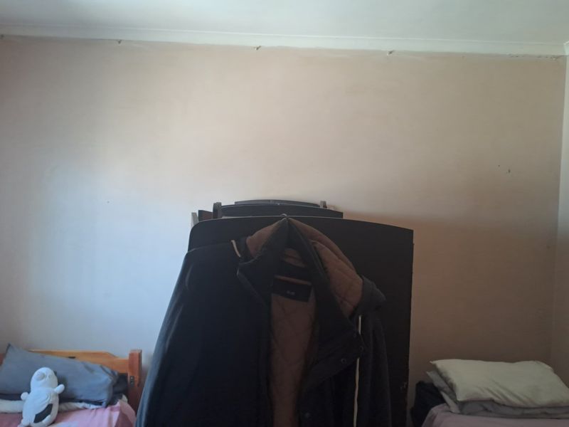 A bedroom featuring plain walls and coving, currently showing signs of wear and requiring cosmetic updates to improve the overall aesthetic.