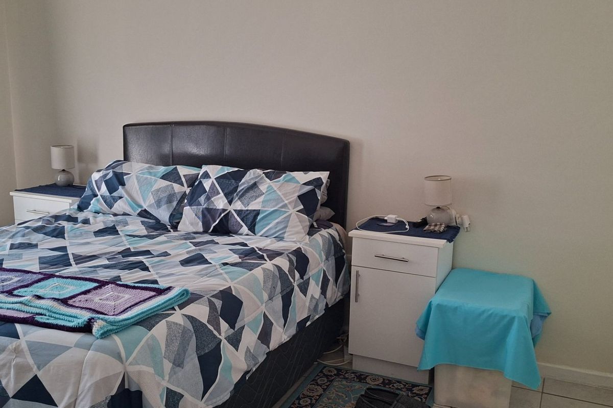 A functional bedroom featuring tiled flooring and a built-in wardrobe, providing a clean and neutral space for rest.