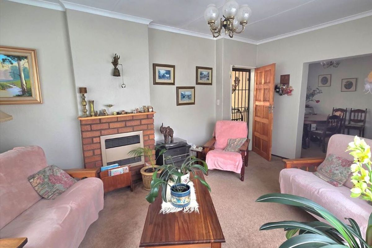 A traditional living room featuring a brick fireplace with a gas heater insert, coved ceilings, and access to adjacent living spaces.