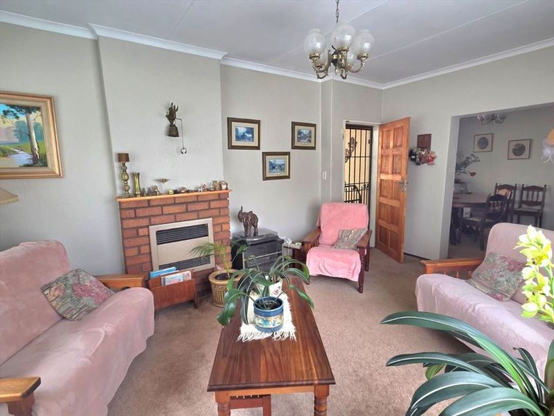 A traditional living room featuring a brick fireplace with a gas heater insert, coved ceilings, and access to adjacent living spaces.