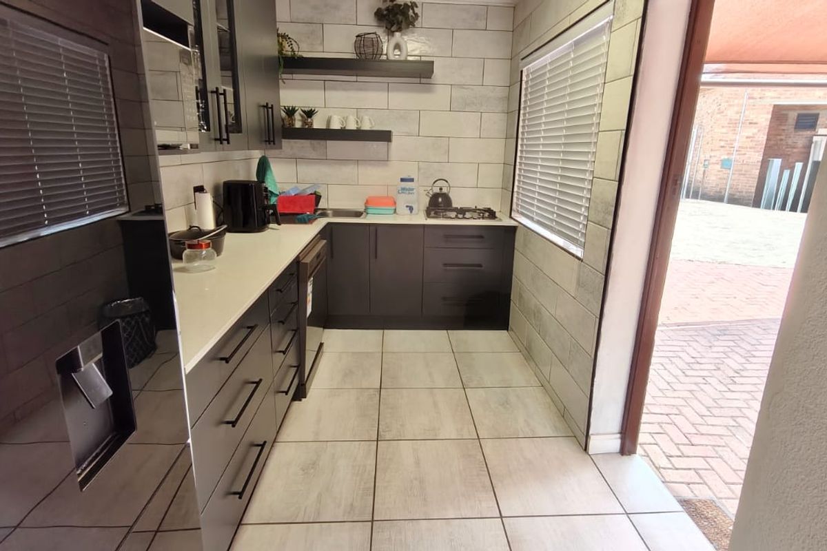 Modern kitchen featuring dark cabinetry, stone countertops, gas hob, and tiled flooring with direct access to the outdoor area.