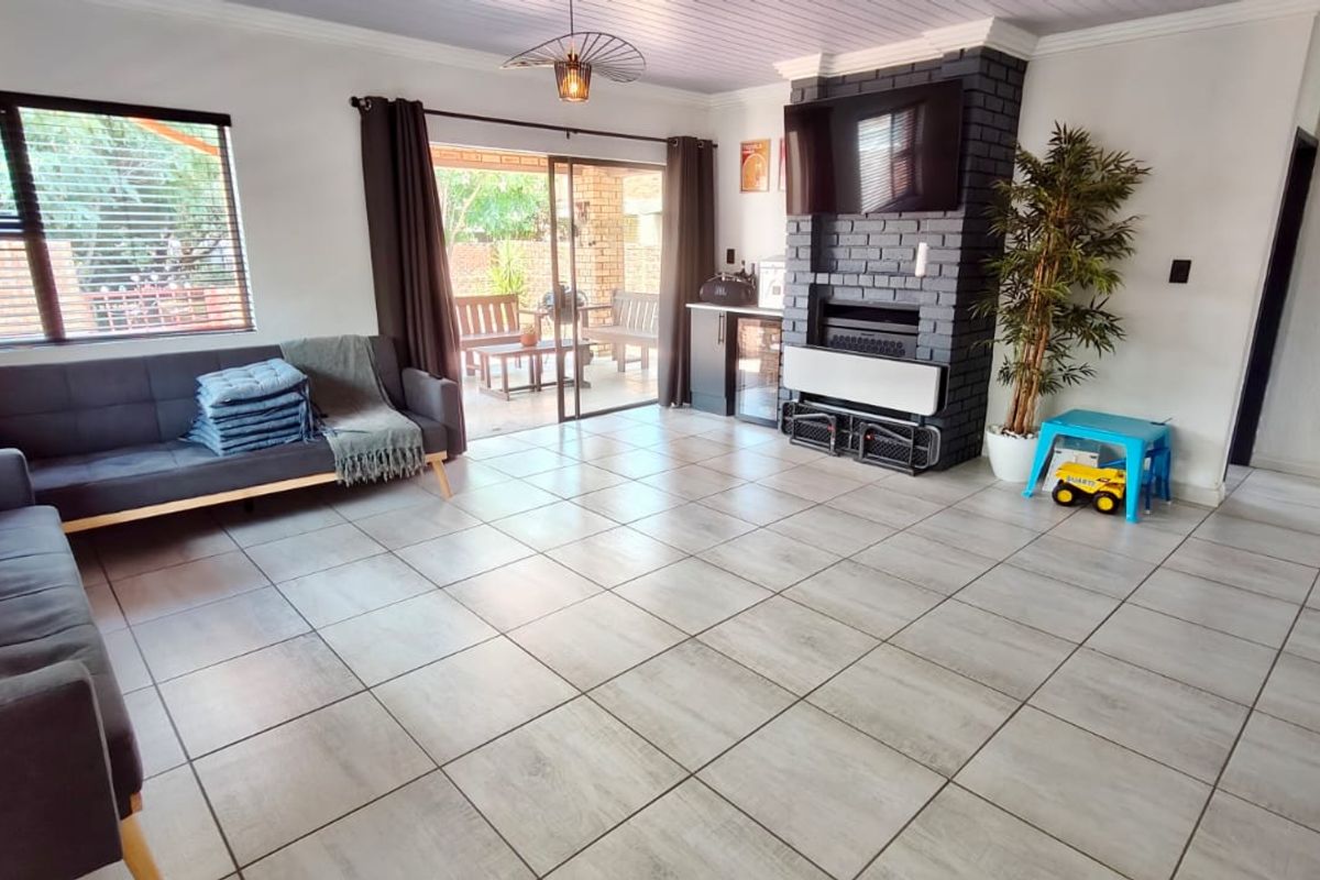 Spacious living room featuring tiled flooring, a prominent brick fireplace, and sliding glass doors providing direct access to the outdoor patio area.
