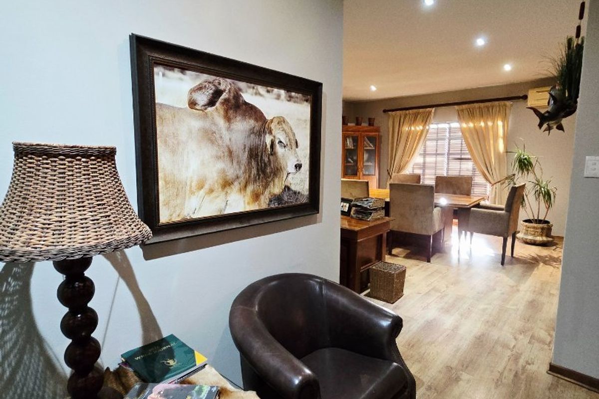 A view from a hallway into an open-plan living and dining area featuring modern laminate flooring and recessed ceiling lighting.
