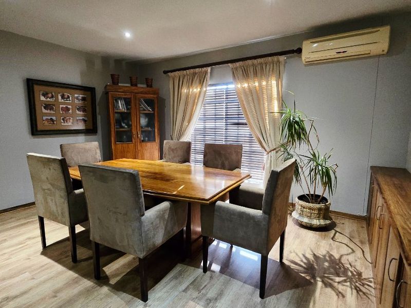 A well-maintained dining room featuring laminate flooring, recessed downlighting, and a wall-mounted split-system air conditioner for climate control.
