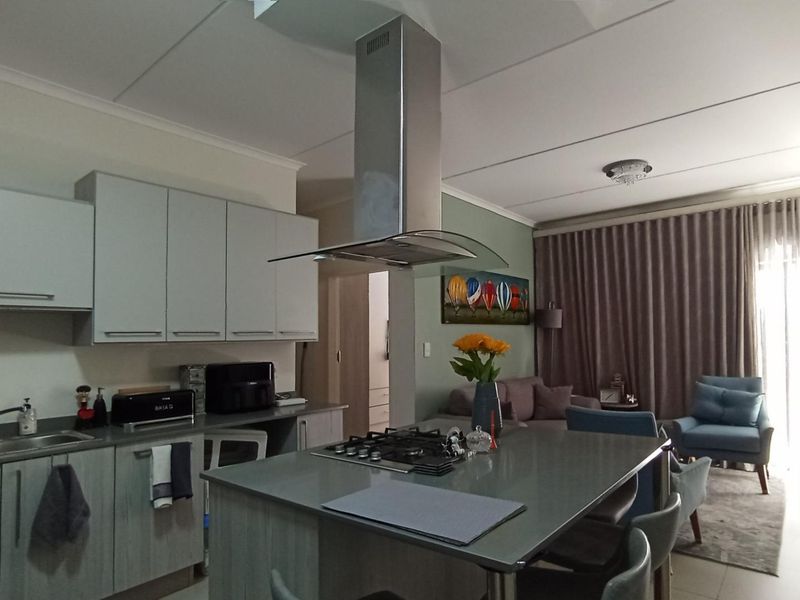 Open plan kitchen and living area featuring a central island with gas hob, extractor fan, and modern cabinetry.