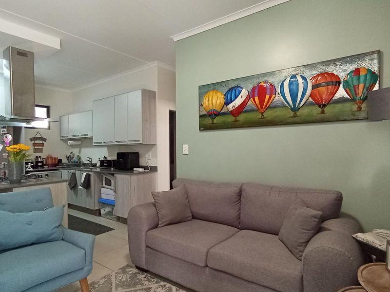 Open-plan living area featuring a modern kitchen with built-in cabinetry, stainless steel extractor fan, and a functional island, seamlessly connected to the lounge space.