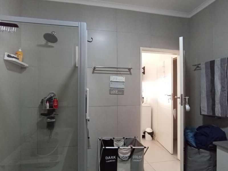 A functional bathroom featuring a glass-enclosed shower, tiled walls, and a vanity basin, providing a clean and practical space.