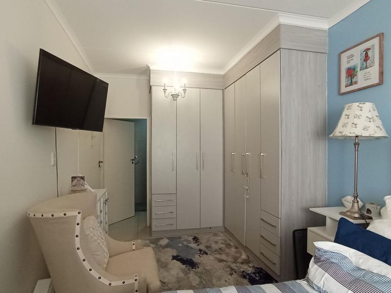 A well-maintained bedroom featuring extensive built-in cabinetry with integrated storage and neutral finishes.