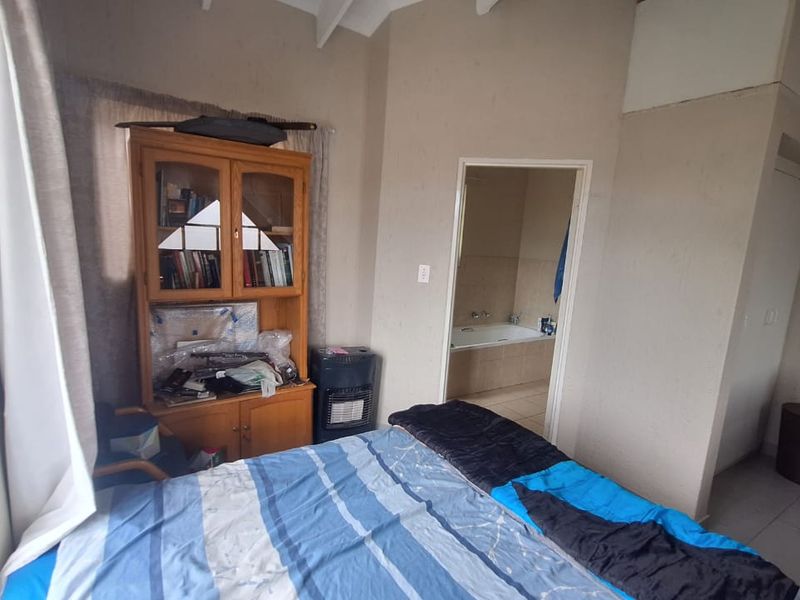 Bedroom featuring tiled flooring, a vaulted ceiling, and an adjoining en-suite bathroom with a built-in cupboard.