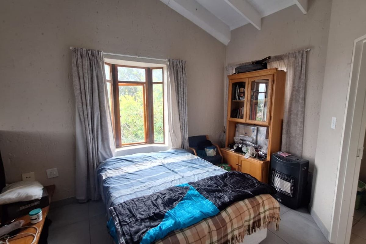A bedroom featuring a vaulted ceiling, tiled flooring, and a bay window, with direct access to an en-suite bathroom.