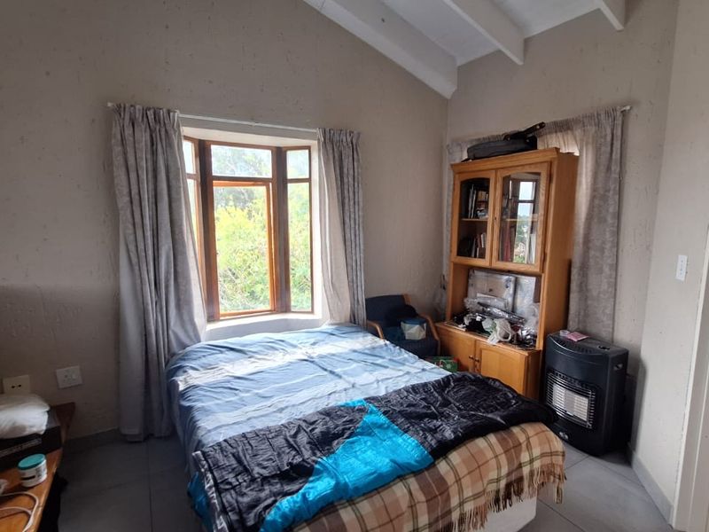 A bedroom featuring a vaulted ceiling, tiled flooring, and a bay window, with direct access to an en-suite bathroom.