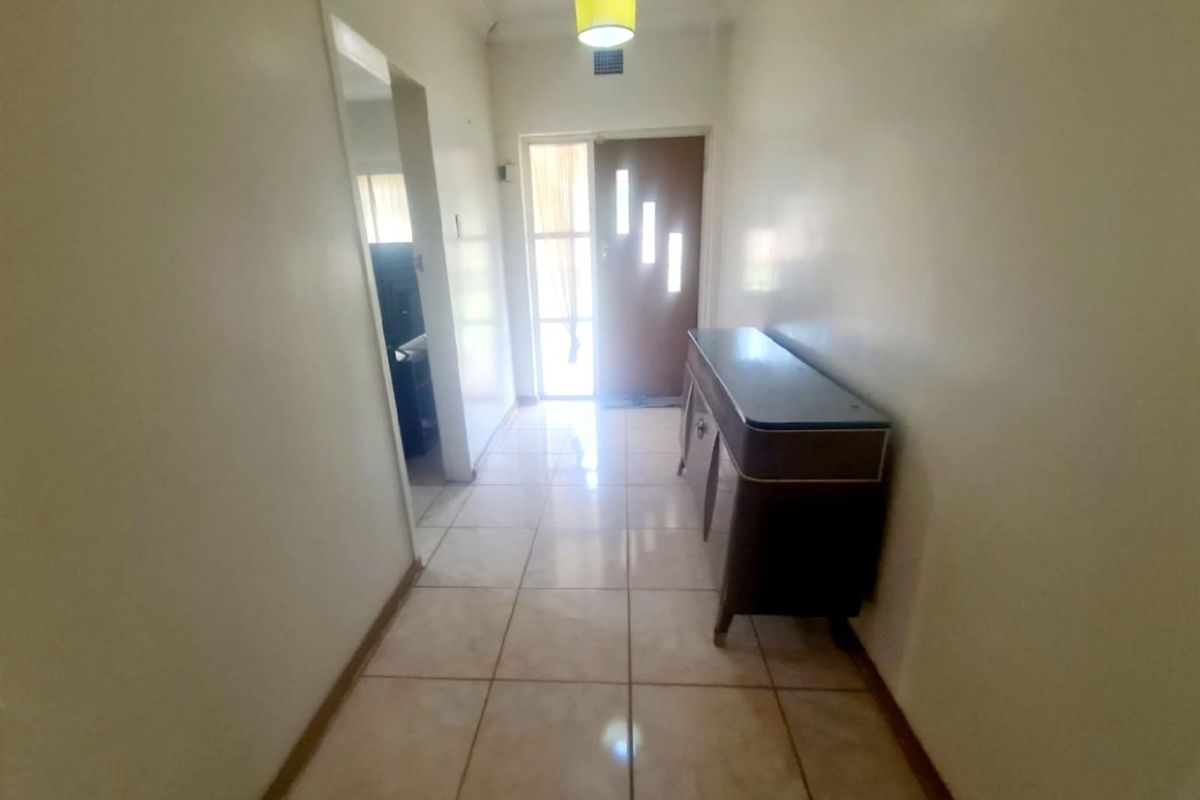 A functional entrance hallway featuring tiled flooring and a front door with glass panels, providing a bright and welcoming transition into the home.