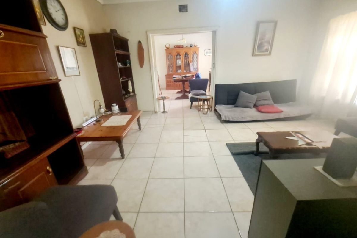 Spacious living area featuring ceramic floor tiles and a neutral color palette, providing a functional layout with direct access to the adjacent dining room.