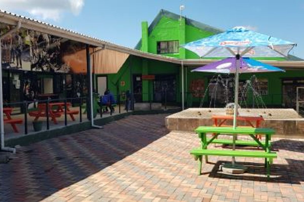 A commercial outdoor courtyard area featuring paved flooring, a covered walkway, and a central water feature.