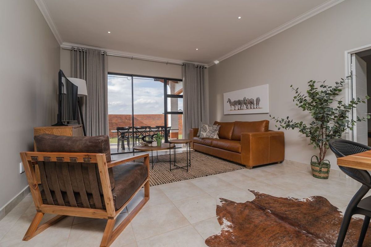 A well-lit living room featuring tiled flooring, recessed downlights, and large sliding glass doors that provide seamless access to the outdoor patio area.