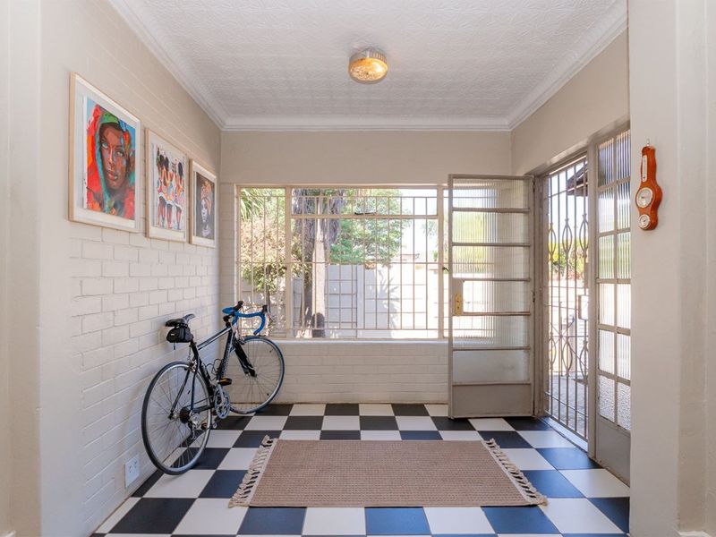 Bright entrance hall featuring classic checkerboard tile flooring, painted brick walls, and secure metal gate access.