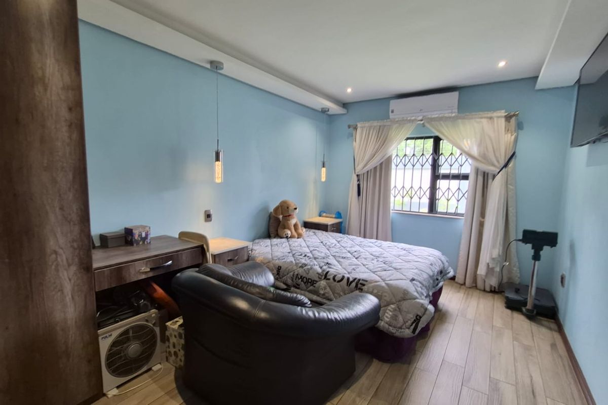 A bedroom featuring wood-look tile flooring, air conditioning, and security bars on the window.