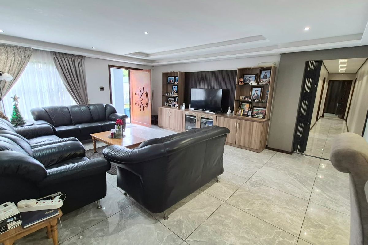 Spacious living room featuring large format floor tiles, recessed ceiling lighting, and custom built-in cabinetry for media storage.