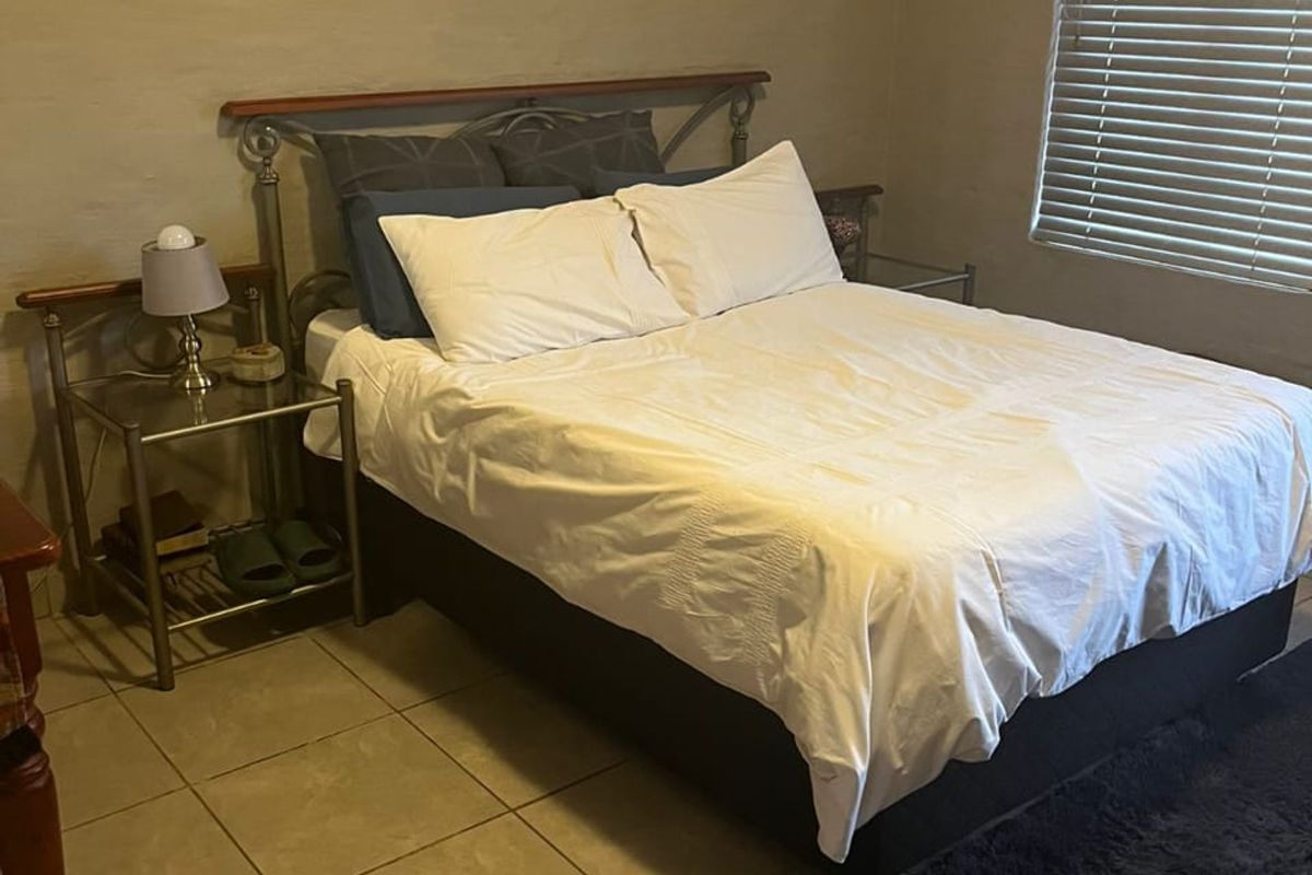 A functional bedroom featuring tiled flooring and venetian blinds, providing a neutral base for potential interior updates.